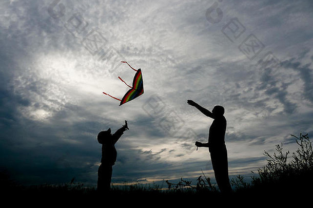 年轻的父亲儿子飞行风筝日落