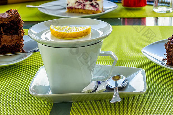 在自助餐厅的桌子上放上一杯白瓷杯加柠檬、糖、汤匙的茶。