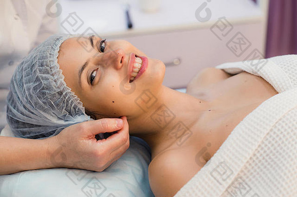 美丽的年轻的女人说谎放松水疗中心沙龙接收面部按摩