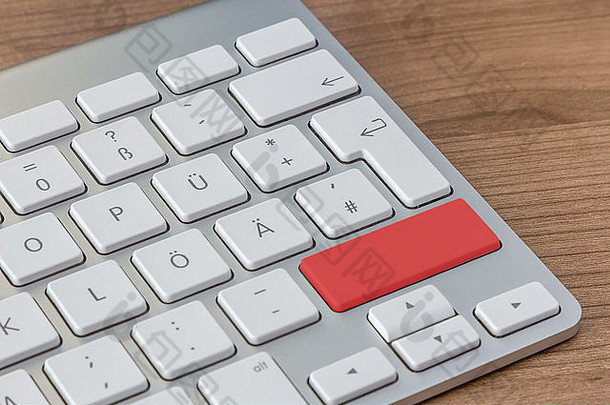 木制桌面上现代键盘的红色大按钮