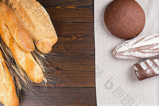 木桌上各种法式面包和甜面包的黑麦卷边俯视图