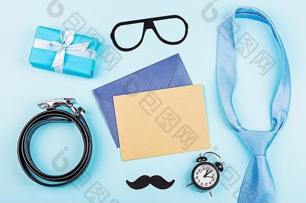 “父亲节快乐”背景，带有礼品盒、皮带、有趣的小胡子、闹钟、桌面上的文本空白纸。平铺式