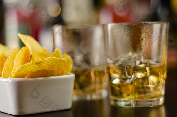 聚会时，在酒瓶和酒吧的背景上放一杯威士忌、冰块和<strong>咸点心</strong>