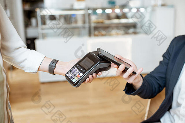 坐在咖啡馆，用智能手机支付非接触式费用的商人，特写镜头