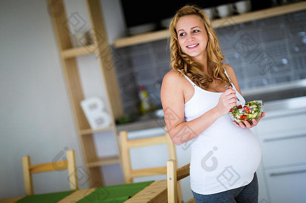 美丽的怀孕了女人吃健康的食物沙拉