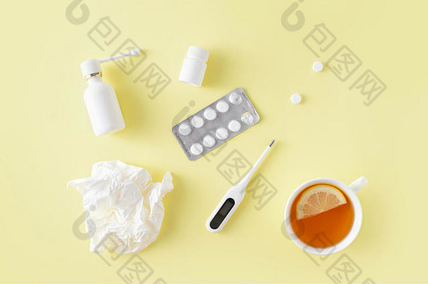 感冒和流感治疗套装。药丸，咽喉喷雾剂，体温计，一杯柠檬茶，简单的黄色背景。保健治疗。平铺，顶六