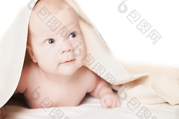 可爱的婴儿沐浴后躺在毛巾下微笑