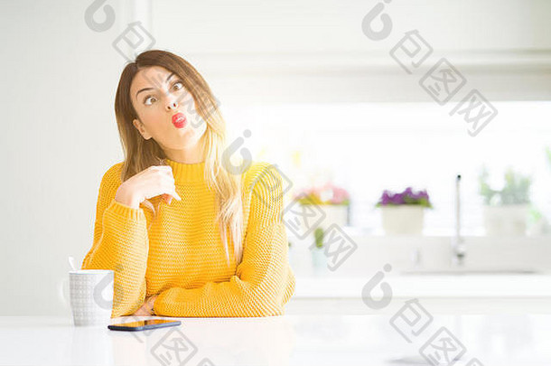 年轻漂亮的女人在家喝一杯咖啡，用嘴唇做鱼脸，疯狂而滑稽的手势。滑稽的表情。