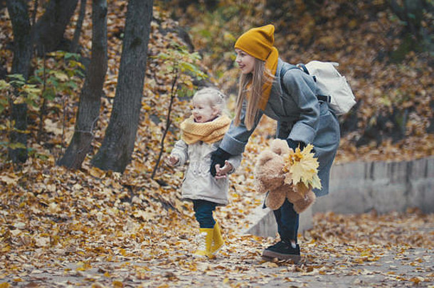 金发小女孩和妈妈在秋天公园收集树叶，特写