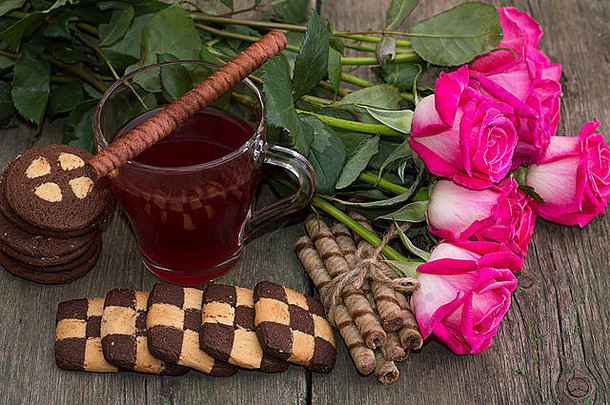 木桌上的玫瑰、饼干和茶构成了美丽的静物画