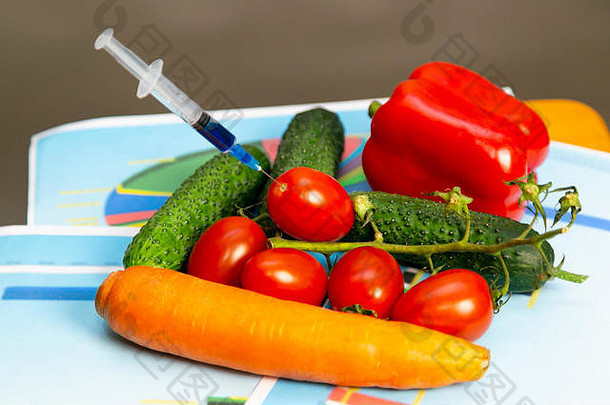 两个装有硝酸盐和杀虫剂的注射器放在一盒蔬菜和水果上