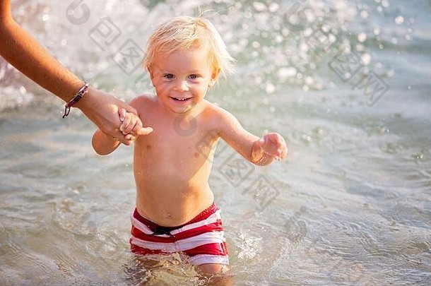 快乐儿童<strong>的</strong>夏日和游泳活动。孩子跳进水里，开心地笑着，溅起水花，<strong>妈妈牵</strong>着他<strong>的手</strong>