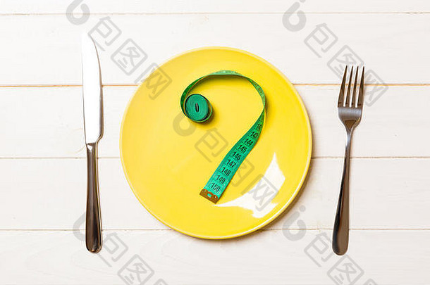 叉子和盘子，彩色背景上有卷尺。饮食观念