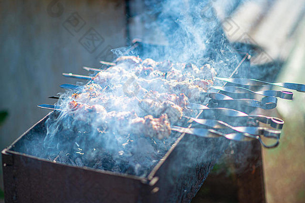 夏天在露天烤羊肉串。烤肉串在烤架上用煤烟炸。