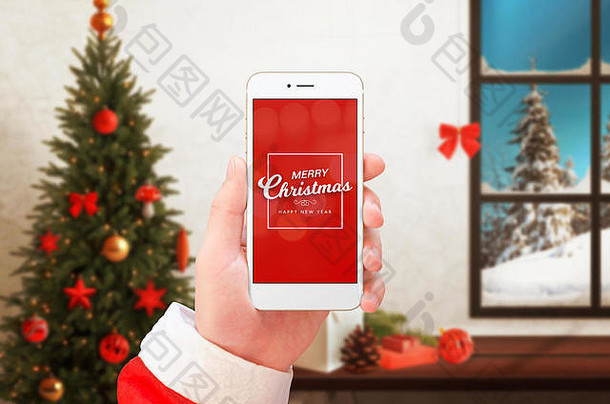 圣诞老人手中的手机显示圣诞快乐和新年祝福。背景中的圣诞树和装饰品。