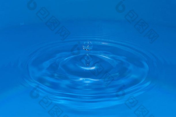由下落的水滴产生的圆形水波，其顶部有一个圆形水滴反弹