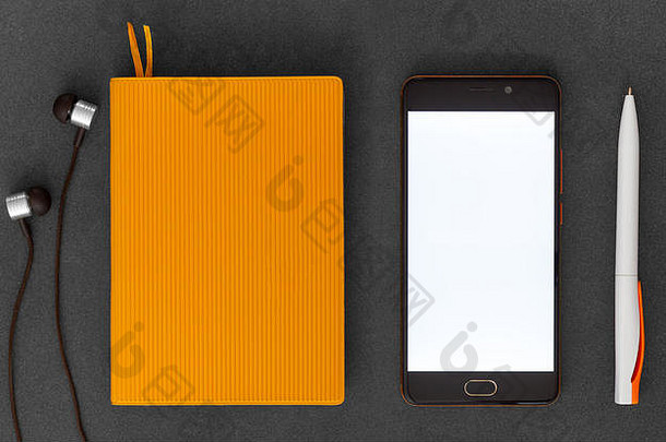 橙色纸笔记本移动电话笔耳机黑暗背景前视图