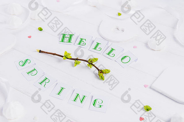 近景构图：Hello spring字样、绿树嫩枝、梅伦格糖果和糖果心、手工制作的鸟形图案