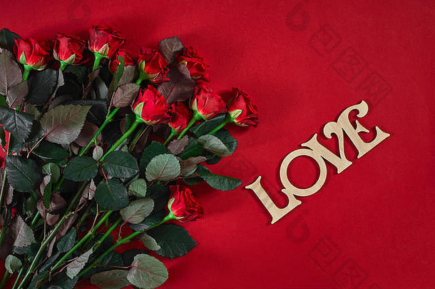 在红色背景上为瓦伦特写美丽的红玫瑰花束