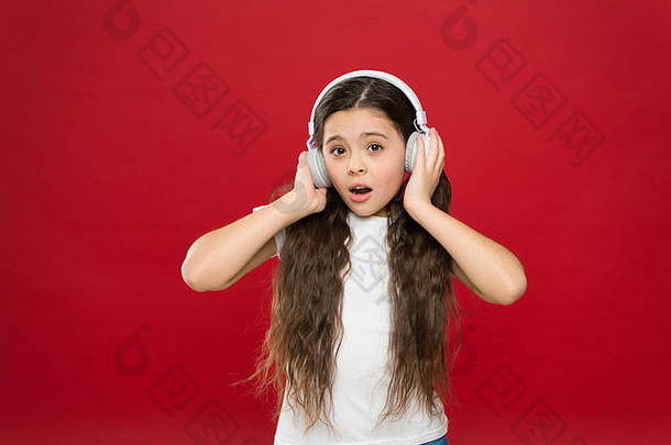 音乐在青少年的生活中起着重要的作用。音乐对青少年的情感、感知世界有着强大的影响。女孩戴着红色背景的耳机听音乐。现代小工具概念。音乐品味。