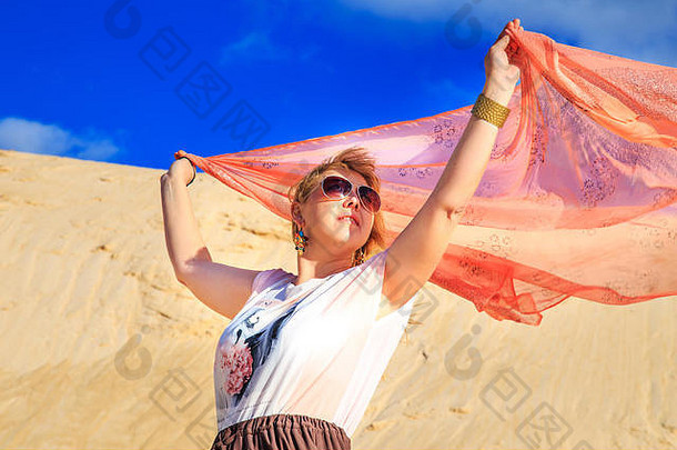 沙漠中穿着粉红色衣服的金发美女。放松和自由的概念。