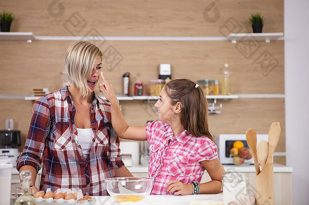母亲和女儿一边做饭一边玩面粉。父母的爱。