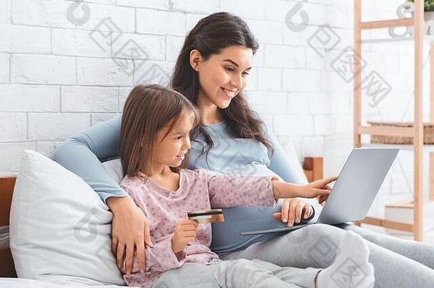 怀孕的母亲和女儿使用笔记本电脑在线购物