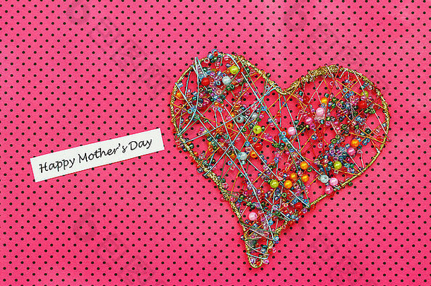 母亲节快乐卡，心形由粉红色圆点背景上的彩色珠子制成