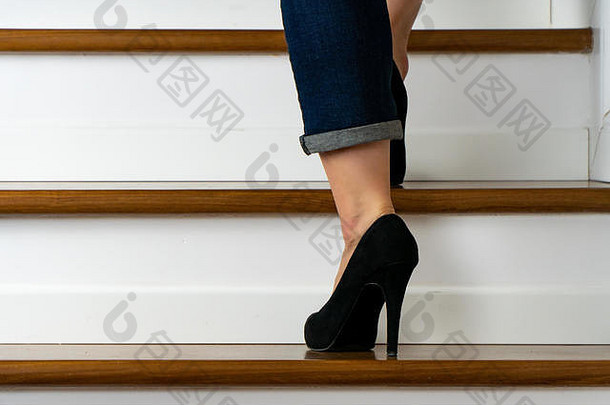 穿着高跟鞋和牛仔裤上楼梯的女孩