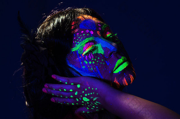 头像上的女人脸上涂着令人敬畏的夜光，蓝色和其他霓虹灯<strong>颜色搭配</strong>，背景模糊抽象，面对着摄像机