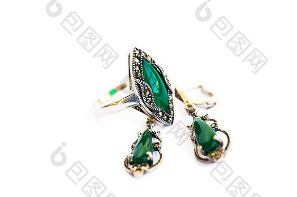 白色背景上镶嵌绿色宝石的耳环和戒指。
