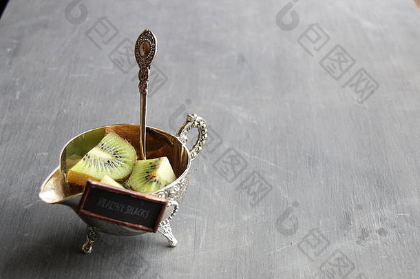 健康晚餐创意标签和银碗猕猴桃。食物背景。