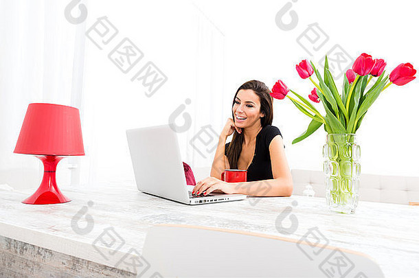 一位年轻漂亮的女士在家里使用笔记本电脑。