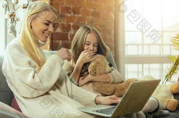 心在<strong>温暖</strong>。幸福的家庭。母亲和女儿一起在家度过时光。看电影，使用笔记本电脑，大笑。<strong>母亲节</strong>，庆祝活动，周末，节日，童年的概念。