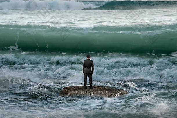 后视图商人站在海洋中的岩石上，面对迎面而来的海浪