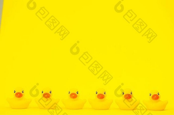 六只黄色的橡皮鸭排在黄色背景空间上