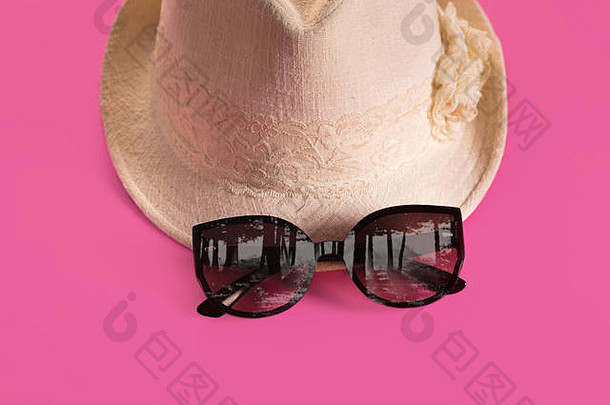 粉色背景的夏日女帽和眼镜