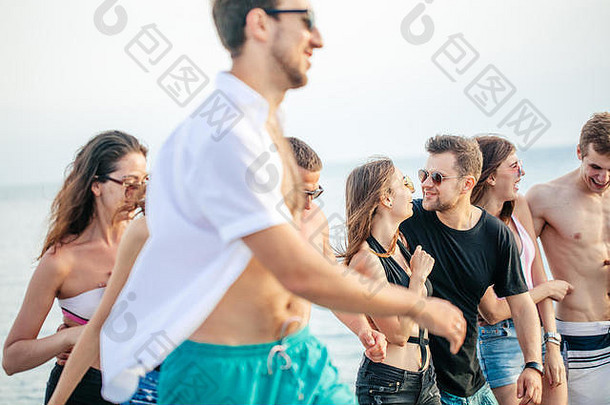 一群朋友在海滩散步，玩得开心，女人背着男人，有趣的假期