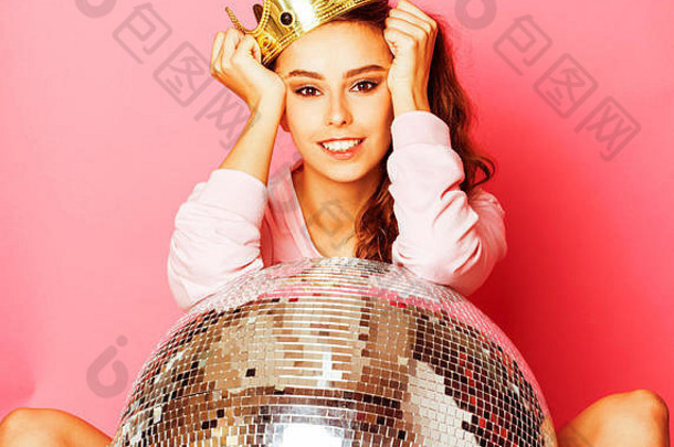 年轻可爱的迪斯科女孩，粉色背景，戴着迪斯科球和皇冠