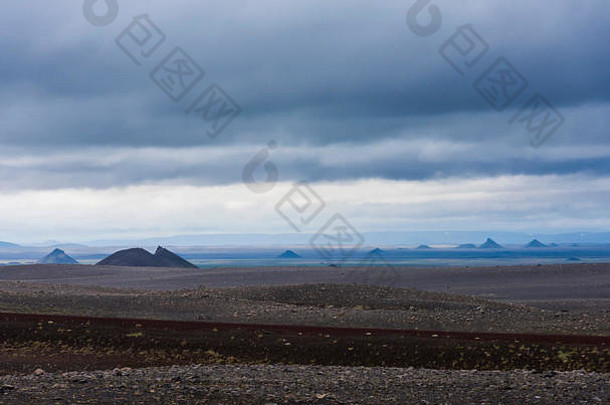 冰岛的火山景观，群山环绕，熔岩、黑砂和乌<strong>云</strong>密布。