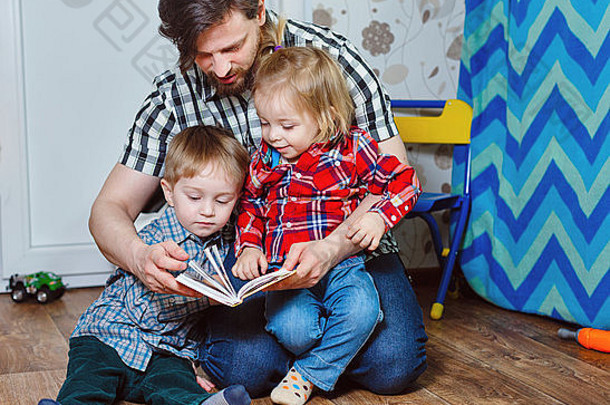 父亲和孩子，兄弟姐妹，坐在托儿所的地板上看书。