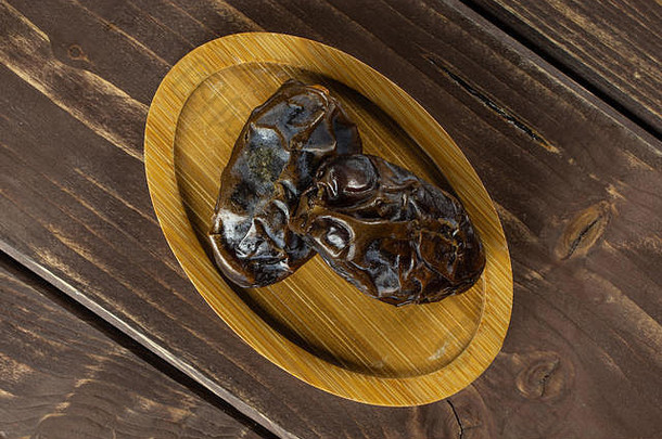 一组两个完整的干棕枣，放在竹板上，平放在棕木上