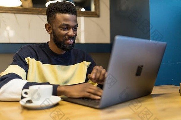 年轻的非洲<strong>网</strong>店经理的个人资料肖像，在笔记本电脑上给他在咖啡馆的伙伴输入信息