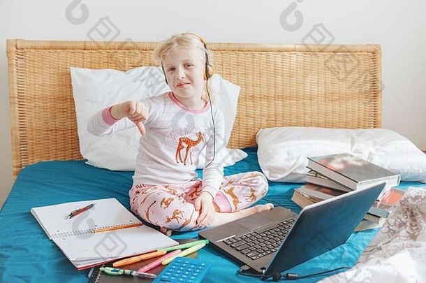 不快乐悲伤的白人女孩坐在床上上<strong>网</strong>学习。在家中自我隔离<strong>期间</strong>的视频虚拟<strong>课</strong>程。远程遥控