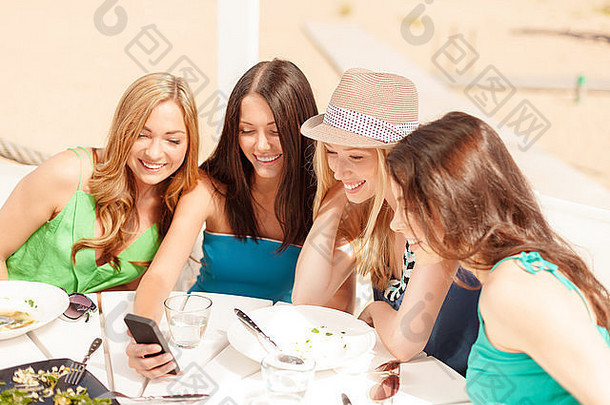 海滩上的咖啡馆里，女孩们看着智能手机