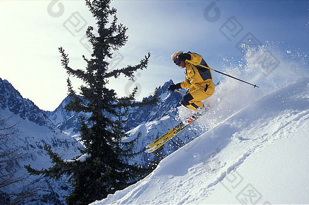 穿着黄色滑雪服的人向前面有树的山谷滑雪