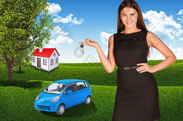 手里拿着钥匙的女人。草地上的小型汽车和房屋