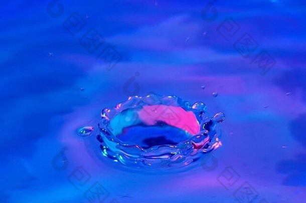 蓝色和粉色灯光下的水花特写图片。