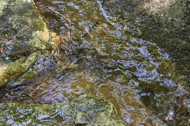 在一个阳光明媚的<strong>夏日</strong>，<strong>清凉</strong>的水在浅溪中的岩石和石头周围流动。
