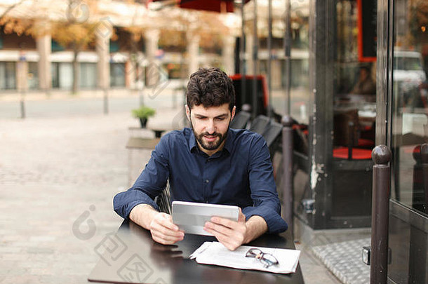一名心怀不满的男子在街边咖啡馆用平板电脑玩网络游戏。